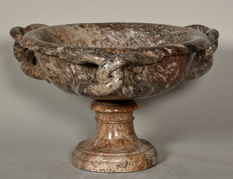 Waza z ciemnego marmuru z trzema splecionymi uchwytami. Waza spoczywa na trzonie z okrągłą stopą. Wewnątrz czary rzeźbiona głowa Meduzy.