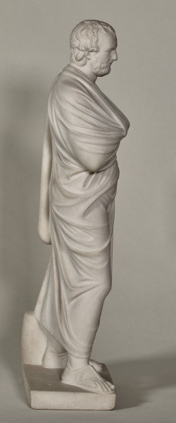 Aischines. Posąg marmurowy przedstawia mężczyznę w średnim wieku okrytego himationem, stojącego ze zgiętą i odsuniętą w bok prawą nogą, z rękoma schowanymi pod szatą, prawa spoczywa na piersiach, lewa z tyłu poniżej pasa. Twarz mężczyzny o wysokim, łysiejącym czole, z wąsami i krótką brodą; jest zamyślona. Bok prawy