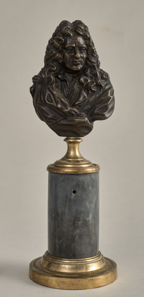 Jean Baptiste Racine. Brązowe, miniaturowe popiersie przedstawia go w starszym wieku, w peruce. Popiersie ustawione jest na podstawie złożonej z brązowego, złoconego cokoliku, cylindrycznego marmurowego trzonu (brak metalowego łańcuszka) i brązowej, złoconej bazy. Przód
