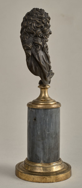 Jean Baptiste Racine. Brązowe, miniaturowe popiersie przedstawia go w starszym wieku, w peruce. Popiersie ustawione jest na podstawie złożonej z brązowego, złoconego cokoliku, cylindrycznego marmurowego trzonu (brak metalowego łańcuszka) i brązowej, złoconej bazy. Bok prawy