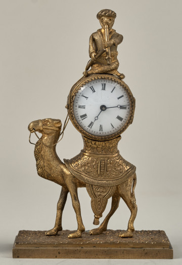 Zegar z wielbłądem z brązu złoconego. Na wielbłądzie znajduje się puszka z mechanizmem, zaś powyżej umieszczono Beduina grającego na instrumencie muzycznym. Za szkłem tarcza biała, emaliowana, na którą naniesiono cyfry rzymskie.