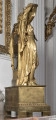 Zegar kominkowy wykonany z brązu złoconego, którego dekoracyjna obudowa przedstawia postaci mitologiczne Dianę trzymającą łuk i Apollina z lirą opartych na prostopadłościennej obudowie werku, która została umieszczona na postumencie w typie sarkofagu, wspartym na czterech prostopadłościennych nóżkach. Bok lewy od tylnej strony.