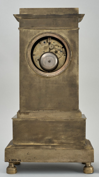 Tył zegara kominkowego w formie architektonicznej w kolorze złotym z widocznym otworem dostępowym do mechanizmu