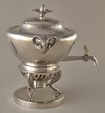 Samowar srebrny z uchwytami w kształcie kozich głów. Stijący na 3 stylizowanych kozich nogach na okrągłej podstawce. Bok lewy