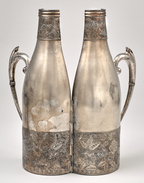 Srebrne etui do butelki, otwarte z widoczną częścią zewnętrzą z dekoracjami roślinnymi.