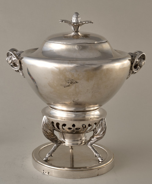 Samowar srebrny z uchwytami w kształcie kozich głów. Stijący na 3 stylizowanych kozich nogach na okrągłej podstawce. Tył