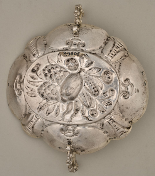 Spód srebrnej tacy z wgłębnym wzorem i widocznym numerem inwentarzowym.