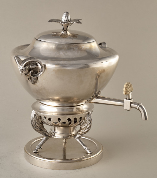 Samowar srebrny z uchwytami w kształcie kozich głów. Stijący na 3 stylizowanych kozich nogach na okrągłej podstawce. Jedno z ujęć.