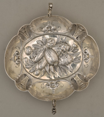 Taca srebrna w ujęciu od góry z widocznym wzorem wytłoczonych warzyw w centralnej części.