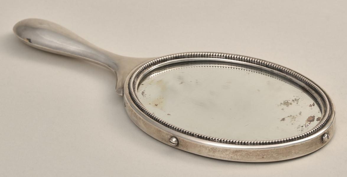 Lusterko dwustronne, damskie srebrne z uchwytem. Jedna ze stron.