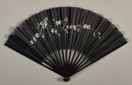 Czarny, otwarty wachlarz z widocznym wzorem kwiatowym ze srebrnej nici. Widok od strony lica.