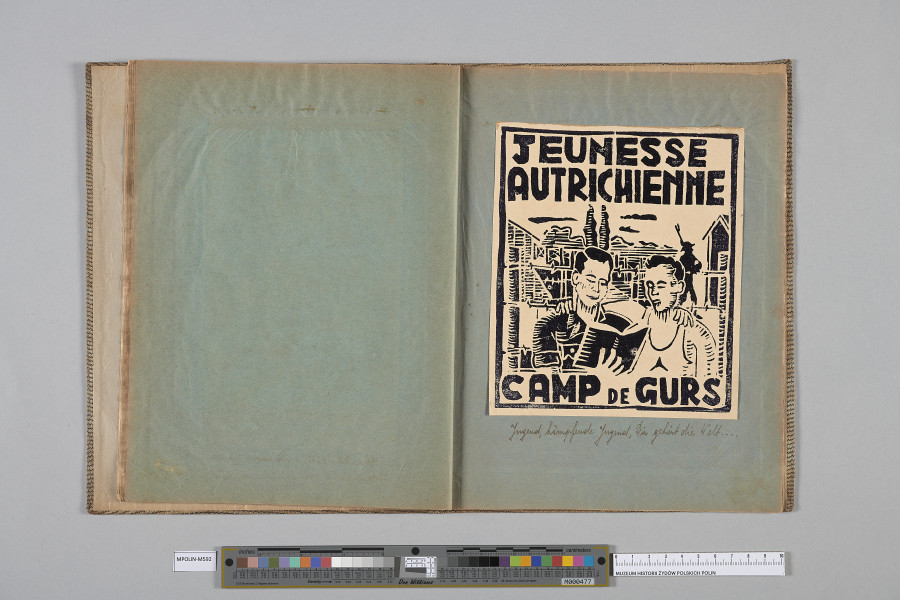 Ujęcie od góry. Rozłożony zeszyt z grafiką naklejoną na prawą kartę. Grafika przedstawia  dwójkę mężczyzn w półobjęciu (ujętych w półpostaci, frontalnie), jeden trzyma książkę, drugi ubrany w jasny podkoszulek z trójramienną gwiazdą na piersi.