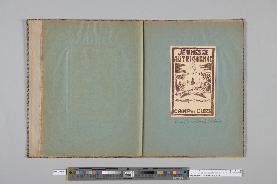 Ujęcie od góry. Rozłożony zeszyt z grafiką naklejoną na prawą kartę. Grafika przedstawia  popiersie nagiego mężczyzny o jasnych włosach, en face.