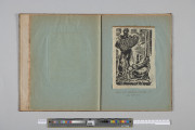Ujęcie od góry. Rozłożony zeszyt z grafiką naklejoną na prawą kartę. Grafika przedstawia  dwóch mężczyzn, jeden stojący, z akordeonem, drugi, po prawej, półleżący, z książką.