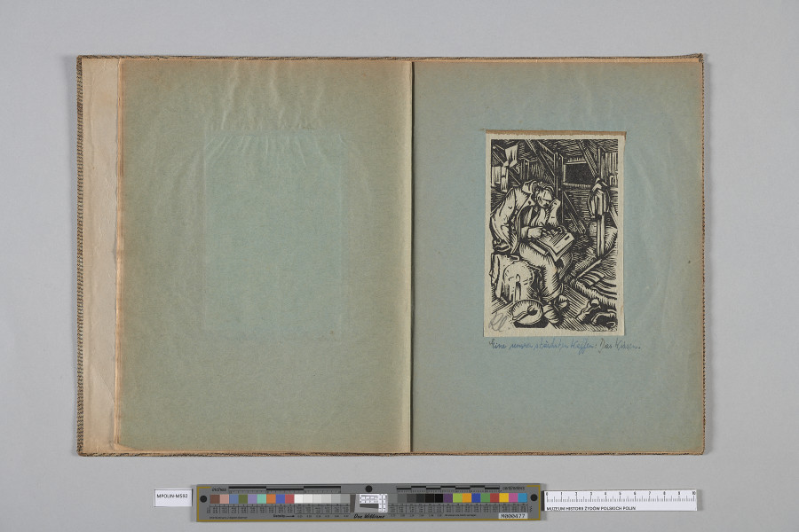 Ujęcie od góry. Rozłożony zeszyt z grafiką naklejoną na prawą kartę. Na grafice mężczyzna ujęty w trzech czwartych, w całej postaci, siedzący w płaszczu i piszący na kartach umieszczonych na książce na kolanach.