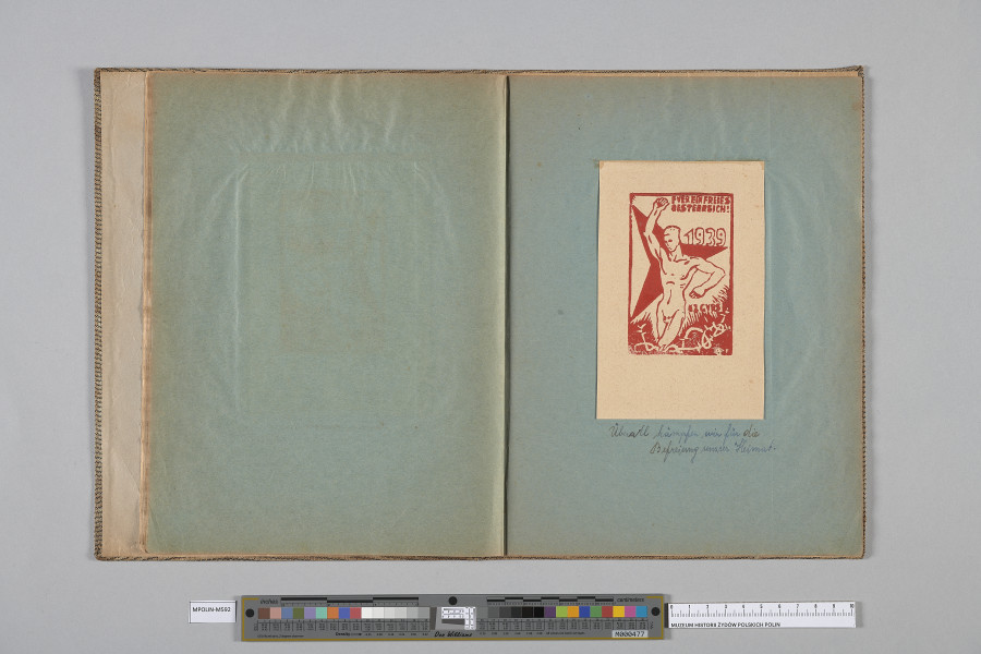 Ujęcie od góry. Rozłożony zeszyt z grafiką naklejoną na prawą kartę. Grafika przedstawia nagiego mężczyznę, ujętego prawie frontalnie.