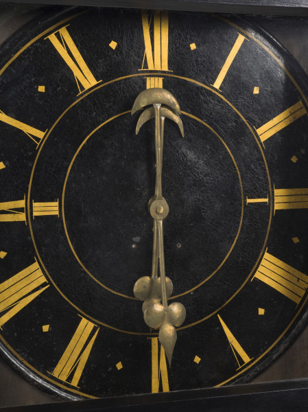 zbliżenie na mosiężne wskazówki oraz stalową, malowaną tarczę zegara