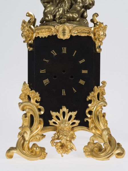 zbliżenie na tarczę zegara oraz dekoracyjne, złocone brązy