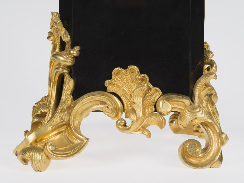 zbliżenie na tarczę zegara oraz dekoracyjne, złocone brązy