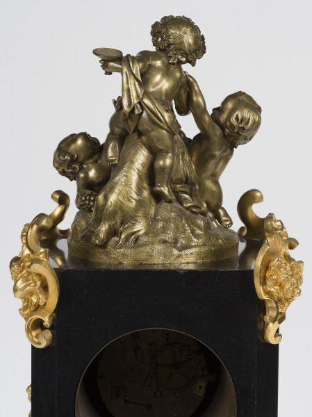 zbliżenie na zwieńczenie z grupą figuralną z brązu patynowanego - mały Bachus w wieńcu winorośli z kielichem w dłoni siedzący na koźle, bawi się z dwoma puttami