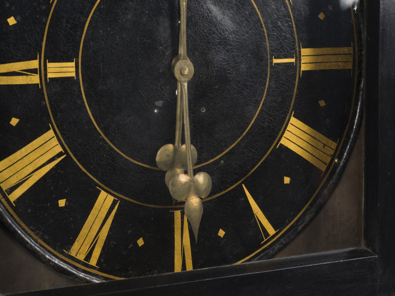 zbliżenie na mosiężne wskazówki oraz stalową, malowaną tarczę zegara