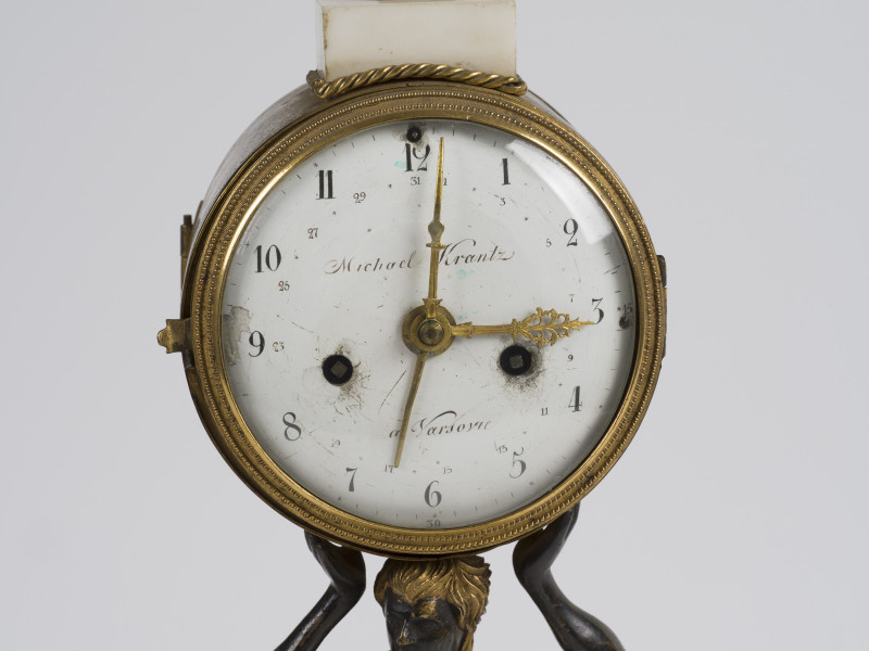 zbliżenie na białą, emaliowaną tarczę zegara oraz mosiężne wskazówki