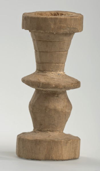 Ujęcie z boku [3]. Ze względu na swój okrągły kształt kolejne ujęcia z boku nie różnią się między sobą znacząco. Wieża została wykonana ręcznie z jednego kawałka jasnego drewna. Na całej powierzchni widoczne są ślady rzeźbienia przy pomocy noża. Obiekt w kolorze naturalnego drewna (nie został pomalowany, ani polakierowany). Od spodu widoczne oznaczenie składające się z dwóch przecinających się ze sobą linii („X”), które umożliwia podzielenie bierek pomiędzy dwóch graczy - wszystkie bierki są jednakowego koloru. Wieża składa się ze spłaszczonej podstawy w formie krążka, środkowej części w formie walca szerszego po środku, spłaszczonego cylindrycznego elementu, który zwęża się stopniowo ku górze oraz ku dołowi (przypominając dwa połączone ze sobą talerze, z których każdy skierowany jest dnem do zewnątrz) oraz zwieńczenia w kształcie kielicha, ozdobionego przy pomocy linii (żłobień).