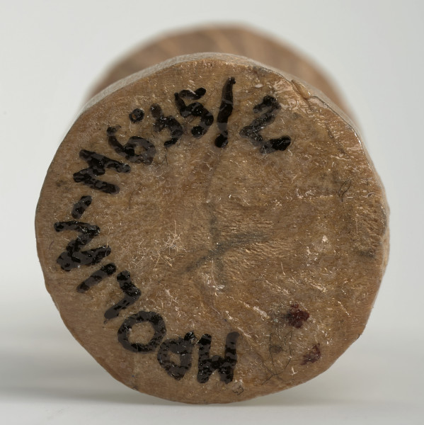 Ujęcie na spód obiektu. Okrągła podstawa pionka szachowego. Ponieważ był on rzeźbiony ręcznie krawędź nie jest idealnie równa. Pośrodku widoczny czarny 