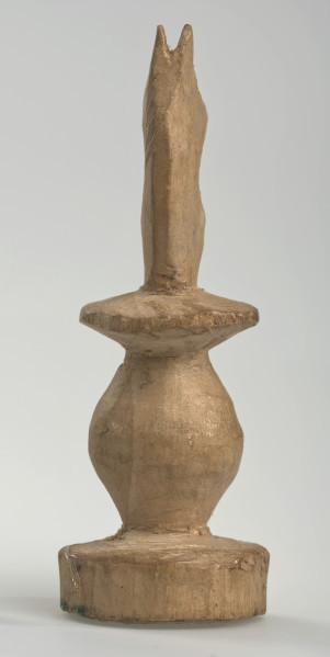 Ujęcie z tyłu. 
Skoczek został wykonany ręcznie z jednego kawałka jasnego drewna. Na całej powierzchni widoczne są ślady rzeźbienia przy pomocy noża. Obiekt w kolorze naturalnego drewna (nie został pomalowany, ani polakierowany). Krawędź podstawy została dodatkowo obrysowana ołówkiem. Skoczek składa się ze spłaszczonej podstawy w formie krążka, części środkowej w formie walca rozszerzającego się po środku wysokości, spłaszczonego cylindrycznego elementu, który zwęża się stopniowo ku górze oraz ku dołowi (przypominając dwa połączone ze sobą talerze, z których każdy skierowany jest dnem do zewnątrz) oraz zwieńczenia w formie nawiązującej do głowy i szyi konia. Głowa oraz szyja są spłaszczone. Widoczna wyżłobiona grzywa z boku.