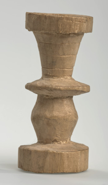 Ujęcie z boku [2]. Ze względu na swój okrągły kształt kolejne ujęcia z boku nie różnią się między sobą znacząco. Wieża została wykonana ręcznie z jednego kawałka jasnego drewna. Na całej powierzchni widoczne są ślady rzeźbienia przy pomocy noża. Obiekt w kolorze naturalnego drewna (nie został pomalowany, ani polakierowany). Od spodu widoczne oznaczenie składające się z dwóch przecinających się ze sobą linii („X”), które umożliwia podzielenie bierek pomiędzy dwóch graczy - wszystkie bierki są jednakowego koloru. Wieża składa się ze spłaszczonej podstawy w formie krążka, środkowej części w formie walca szerszego po środku, spłaszczonego cylindrycznego elementu, który zwęża się stopniowo ku górze oraz ku dołowi (przypominając dwa połączone ze sobą talerze, z których każdy skierowany jest dnem do zewnątrz) oraz zwieńczenia w kształcie kielicha, ozdobionego przy pomocy linii (żłobień).