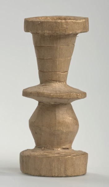 Ujęcie z boku [4]. Ze względu na swój okrągły kształt kolejne ujęcia z boku nie różnią się między sobą znacząco. Wieża została wykonana ręcznie z jednego kawałka jasnego drewna. Na całej powierzchni widoczne są ślady rzeźbienia przy pomocy noża. Obiekt w kolorze naturalnego drewna (nie został pomalowany, ani polakierowany). Od spodu widoczne oznaczenie składające się z dwóch przecinających się ze sobą linii („X”), które umożliwia podzielenie bierek pomiędzy dwóch graczy - wszystkie bierki są jednakowego koloru. Wieża składa się ze spłaszczonej podstawy w formie krążka, środkowej części w formie walca szerszego po środku, spłaszczonego cylindrycznego elementu, który zwęża się stopniowo ku górze oraz ku dołowi (przypominając dwa połączone ze sobą talerze, z których każdy skierowany jest dnem do zewnątrz) oraz zwieńczenia w kształcie kielicha, ozdobionego przy pomocy linii (żłobień).