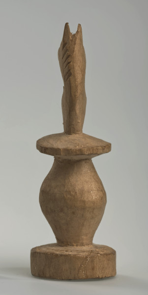 Ujęcie z tyłu.
Skoczek został wykonany ręcznie z jednego kawałka jasnego drewna. Na całej powierzchni widoczne są ślady rzeźbienia przy pomocy noża. Obiekt w kolorze naturalnego drewna (nie został pomalowany, ani polakierowany). Od spodu widoczne oznaczenie składające się z dwóch przecinających się ze sobą linii („X”), które umożliwia podzielenie bierek pomiędzy dwóch graczy - wszystkie bierki są jednakowego koloru. Skoczek składa się ze spłaszczonej podstawy w formie krążka, części środkowej w formie walca rozszerzającego się po środku wysokości, spłaszczonego cylindrycznego elementu, który zwęża się stopniowo ku górze oraz ku dołowi (przypominając dwa połączone ze sobą talerze, z których każdy skierowany jest dnem do zewnątrz) oraz zwieńczenia w formie nawiązującej do głowy i szyi konia. Głowa oraz szyja są spłaszczone. Widoczna wyżłobiona grzywa z boku.