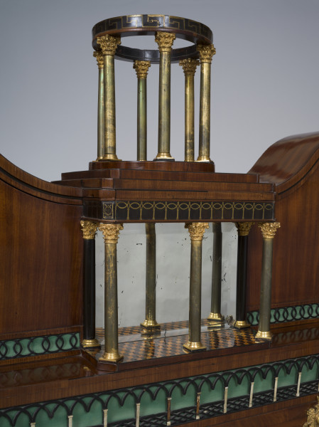 zbliżenie na wypukły portyk na 3 kolumienkach z lustrem w tle, zwieńczony okrągłą altanką wspartą na 6 metalowych kolumienkach przykrytych szkłem