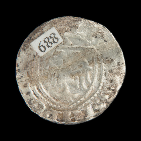 Srebrna moneta pomorska pół szylinga - Ujęcie rewersu. Cienka moneta okrągła, o nieregularnych kształtach. W polu otoczonym perełkowym łańcuszkiem tarcza herbowa, a w niej dwugłowy orzeł. Nad tarczą trzy kropki w układzie trójkątnym. Napis na brzegu.