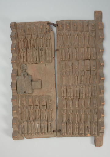 drewniane drzwiczki do spichlerza - Ujęcie z przodu. Dwuczęściowe połączone żelaznymi klamrami drewniane drzwiczki do spichlerza. Całość udekorowana płaskorzeźbionymi postaciami. W środku lewego brzegu zamek.