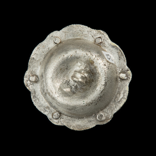 Pozłacany guz w kształcie sześcioramiennej ażurowej rozety - Ujęcie z tyłu. Owalna ozdoba. Spód tłoczony z pełnej blachy, w części centralnej wysklepiony, z płaskim kołnierzem. Środek wklęsły z przylutowanym uszkiem