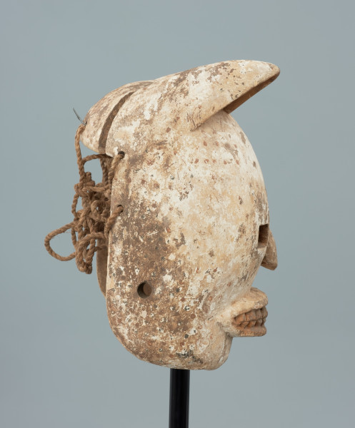 maska - Ujęcie prawego boku. Drewniana, rzeźbiona maska pantery. Głowa zaokrąglona, zwieńczona trójkątnymi, lekko skierowanymi do przodu uszami. Wycięte prostokątne oczy, mały spłaszczony nos. Pysk szeroki, wypukły z widocznymi rzeźbionymi zębami. Całość biała, miejscami przybrudzona. W części tylnej maski wywiercone otwory, umożliwiające przymocowanie jej do twarzy tancerza oraz pozostałości po sznurku.