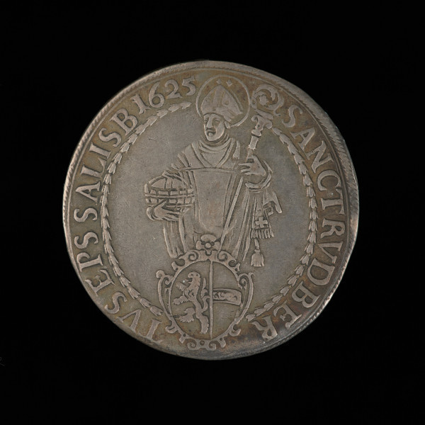 talar - Ujęcie awersu. Na awersie monety nad herbem biskupim półpostać Matki Bożej z Dzieciątkiem na lewej ręce i berłem w prawej dłoni, po bokach łukowaty napis i napis w otoku.