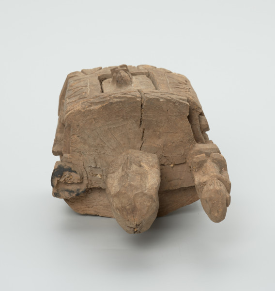 drewniane pudełko na fetysz - Ujęcie z góry. Drewniane pudełko, dekorowane płaskorzeźbami, w środku którego widoczne są drzwiczki.