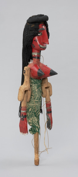 Ujęcie z boku. Drewniana lalka teatralna, z rękoma ruchomymi w ramionach oraz w łokciach.