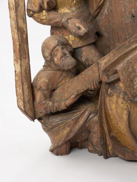 sztuka sakralna, kwatera ołtarza, płaskorzeźba - detal kolejne ujęcie; Płaskorzeźba przedstawiająca Chrystusa pochylonego pod ciężarem krzyża oraz pomagającego mu na rozkaz żołnierzy Szymona Cyrenejczyka. Scena na tle pejzażu górskiego przed murami miasta. Kwatera środkowa późnogotyckiego ołtarza pasyjnego z Wkryujścia (Ueckermünde).