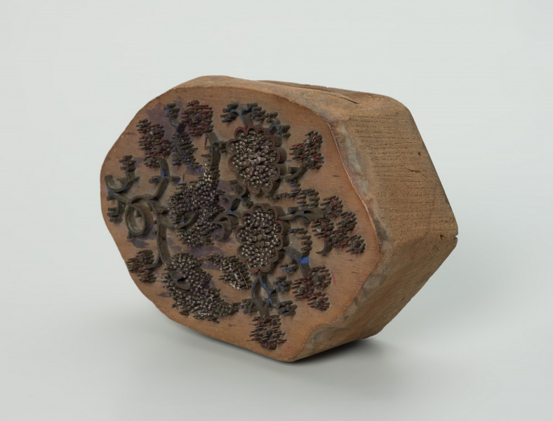 sprzęt do drukowania i grafiki, matryca drukująca - Ujęcie przodu skosem w prawą stronę. Matryca do drukowania tkanin z wykonanym z nabitych w drewno mosiężnych sztyfcików i blaszek ornamentem o motywie roślinnym.