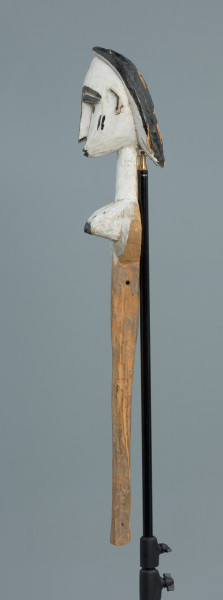 lalka teatralna: Mèrè - Ujęcie z boku z lewej strony. Marionetka przedstawiająca popiersie kobiece o jasnej, białej karnacji. Podłużna głowa okolona włosami z włóczki o wyraźnie zaznaczonych brwiach.