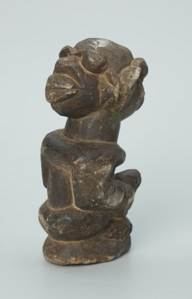 rzeźba; przedmiot obrzędowy; Figura kultu sił wegetacji - Ujęcie z tyłu. Rzeźbiona w grafitowym steatycie siedząca postać ludzka o dwóch twarzach, z przodu i z tyłu głowy.