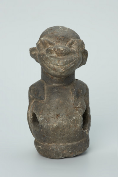 rzeźba; przedmiot obrzędowy; Figura kultu sił wegetacji - Ujęcie z przodu z prawej stony. Rzeźbiona w grafitowym steatycie półpostać o cechach ciężarnej kobiety. W dużym, wydętym brzuchu z czterema otworami umieszczona jest kamienna kula.