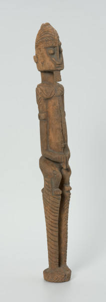 drewniana, rzeźbiona figura - Ujęcie z przodu, z prawej strony. Drewniana, rzeźbiona postać człowieka na szczudłach.