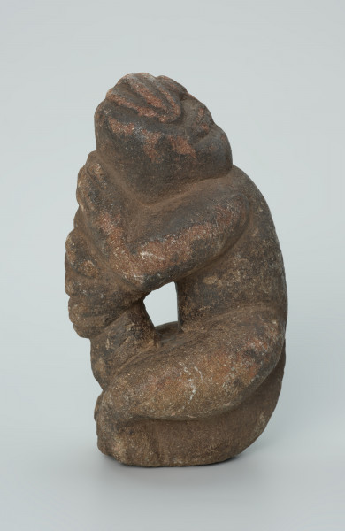 rzeźba; popiersie; Figura kultu zmarłych - Ujęcie lewy bok. Rzeźbione w grafitowobeżowym steatycie popiersie człowieka z jaszczurką, której łapy obejmują głowę i ramiona postaci ludzkiej.