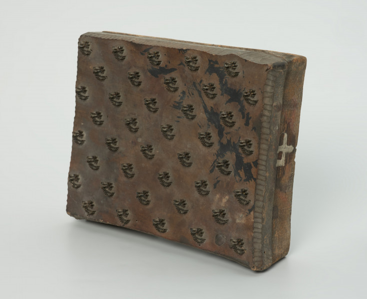 sprzęt do drukowania i grafiki, matryca drukująca - Ujęcie przodu skosem w prawą stronę. Matryca do drukowania tkanin z wykonanym z nabitych w drewno mosiężnych sztyfcików i blaszek ornamentem o motywie roślinnym.