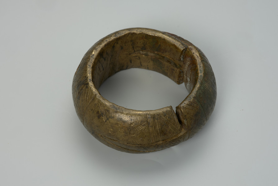 biżuteria, bransoleta - Ujęcie z przodu z góry. Dwuczęściowa, mosiężna, kulista bransoleta składająca się z dwóch wkładanych, półkulistych elementów. Zewnętrzna powierzchnia ozdobiona punktowym wzorem w postaci pionowych i ukośnych linii, kół oraz półkoli. Brak wzoru na bocznym grzebiecie.