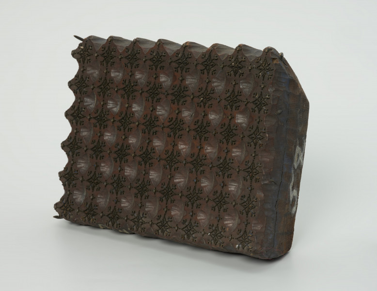 sprzęt do drukowania i grafiki, matryca drukująca - Ujęcie przodu skosem w prawą stronę. Matryca do drukowania tkanin z wykonanym częściowo w drewnie i częsciowo z mosiężnych sztyfcików i blaszekw nie nabitych, ornamencie o motywie roślinno-geometrycznym.